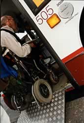 Wheelchair user shown entering a low-floor bus with its access ramp down
